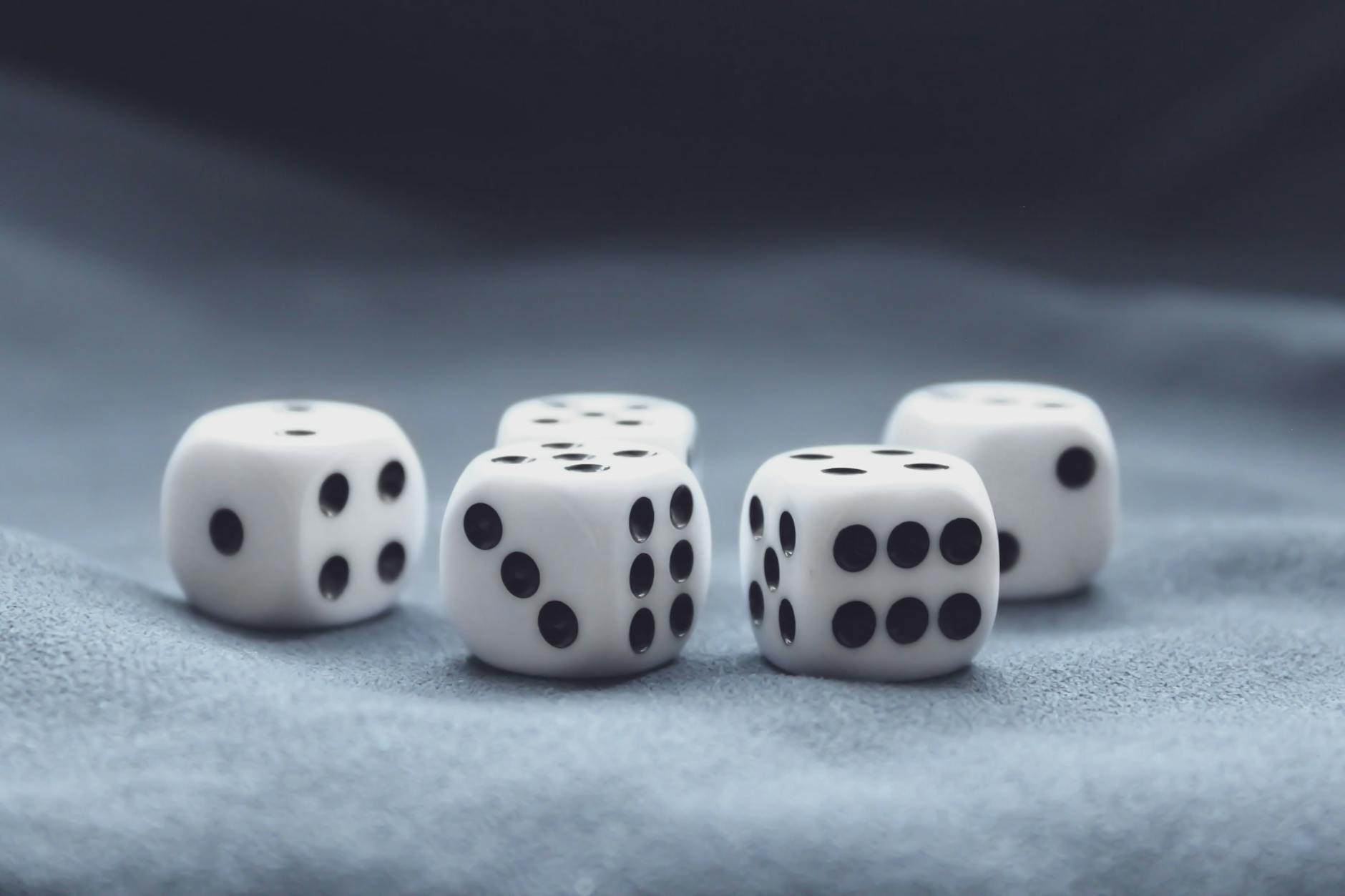 A collection of five white dice on a soft, textured background. Perfect for gaming themes.