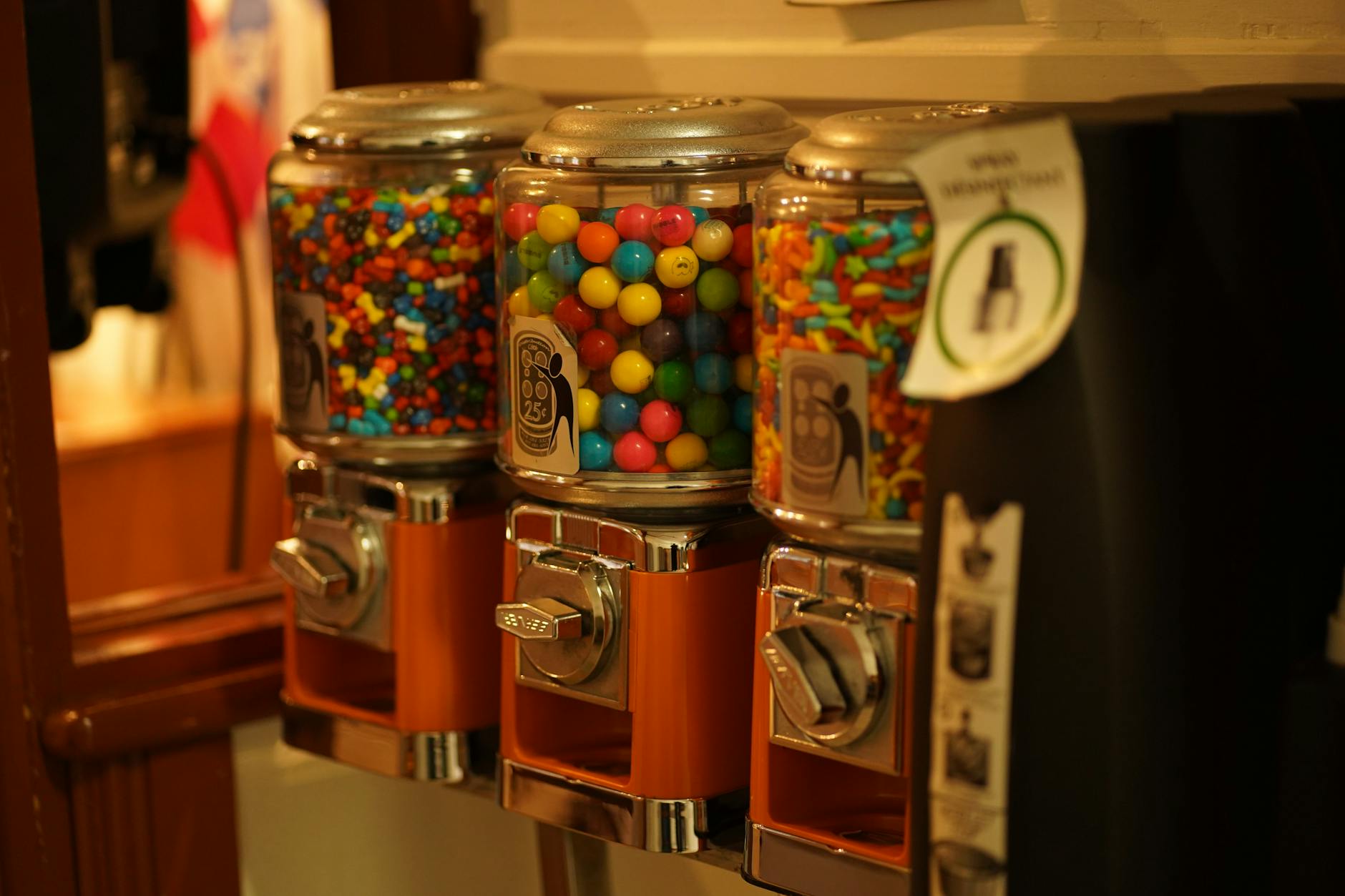 Close-up of colorful candy displayed in vintage vending machines indoors.