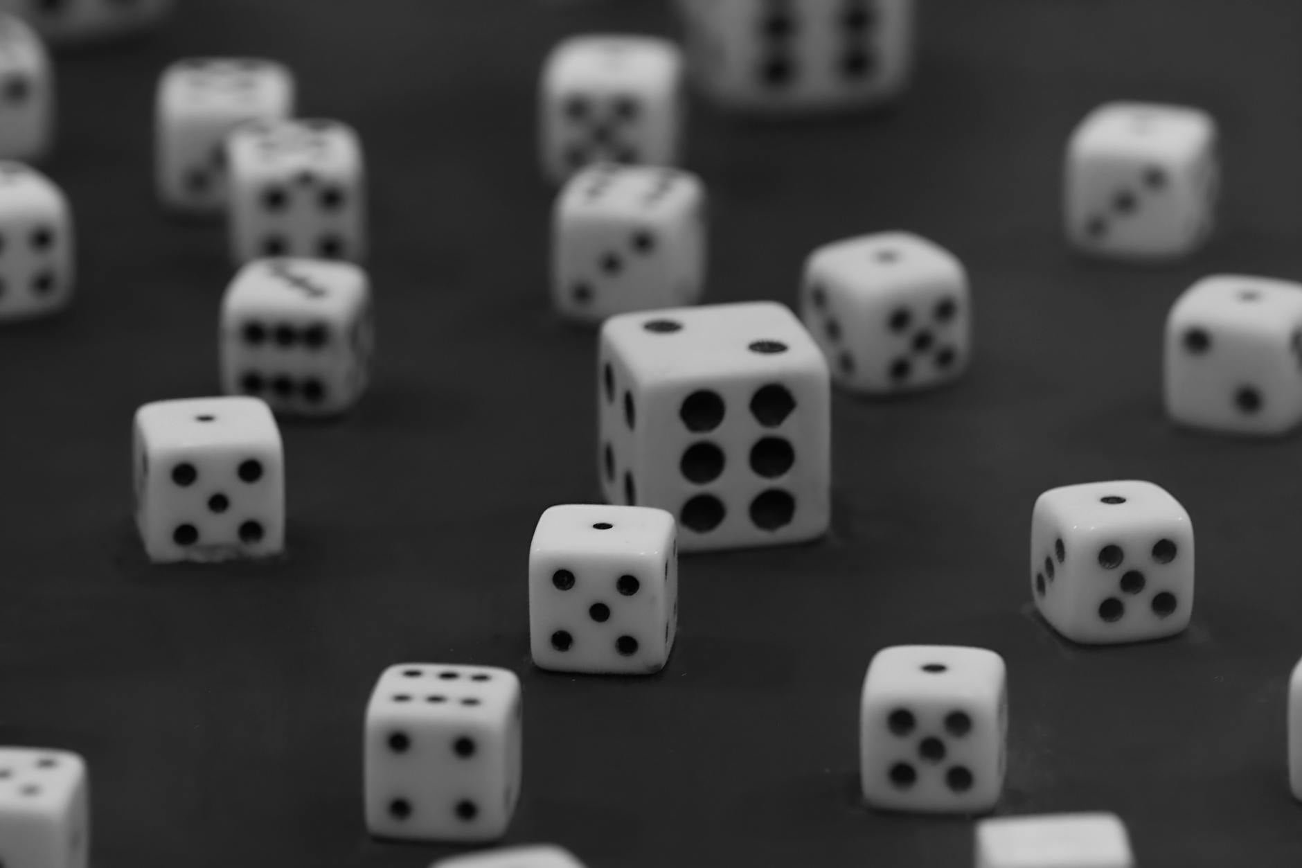 Black and white photo of various dice scattered across a dark surface.