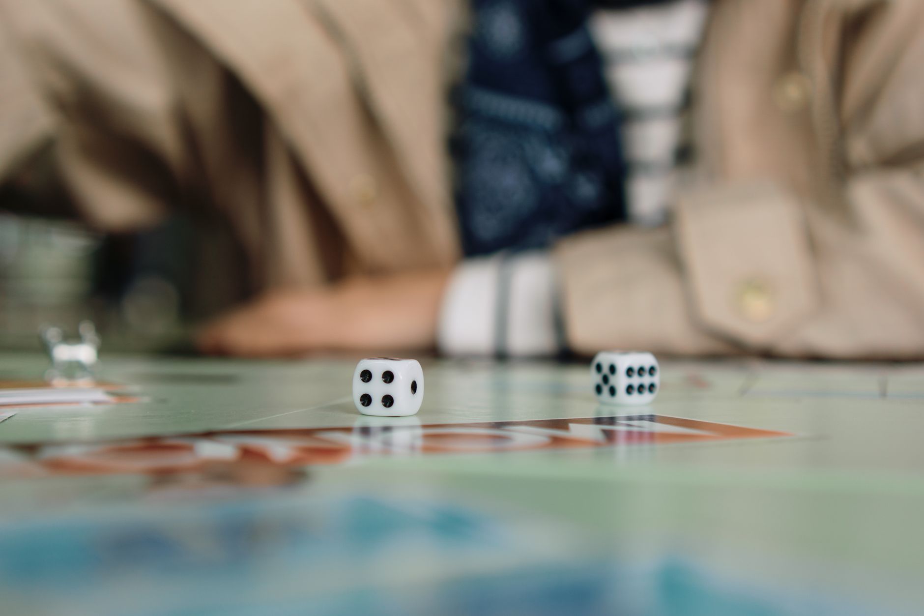 Focused shot of dice in action during a board game with a player in the background.