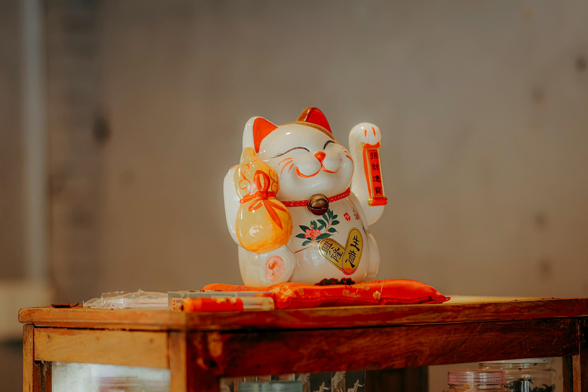 Ceramic maneki neko cat figurine on wooden table, symbolizing luck and prosperity.