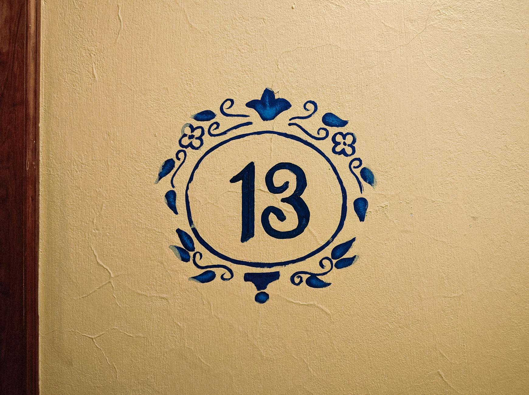Artistic number 13 painted on a textured wall with blue floral design, Naolinco, Mexico.