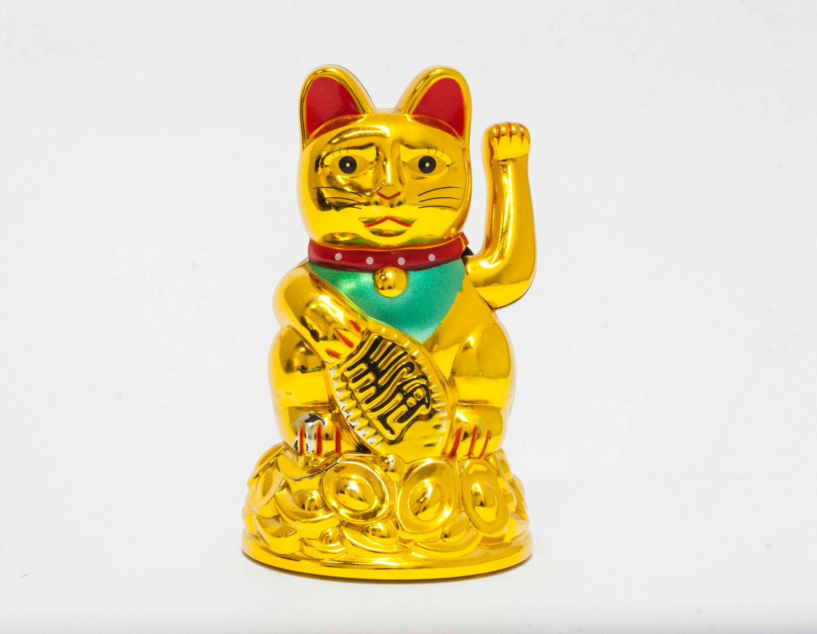 A golden Maneki-neko figurine symbolizing luck and prosperity on a white backdrop.