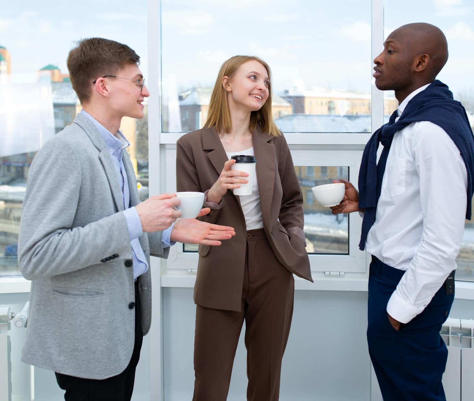 Colleagues enjoying a coffee break, engaging in lively discussion indoors, enhancing teamwork.
