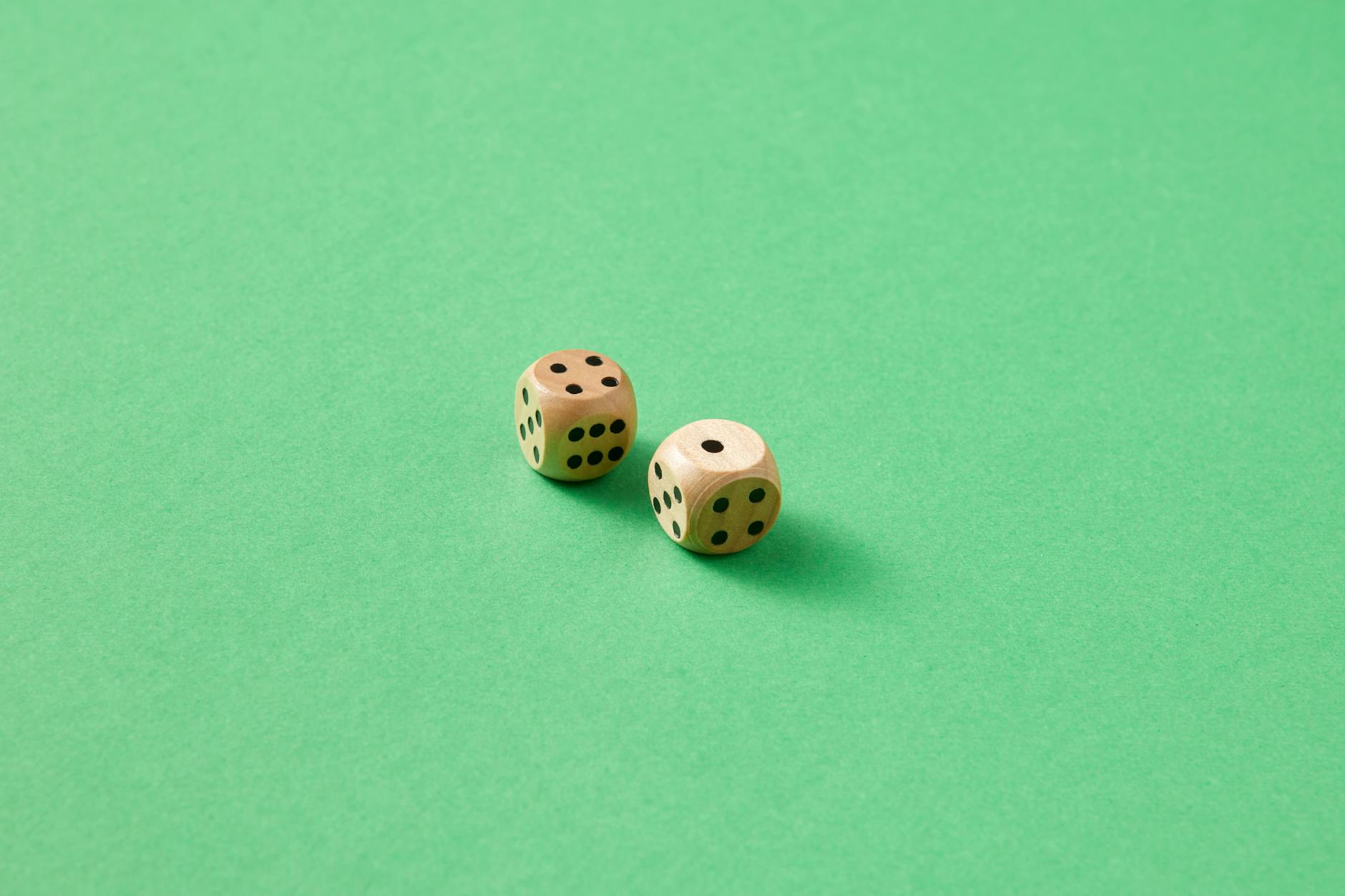Close-up of two wooden dice on a vibrant green background.