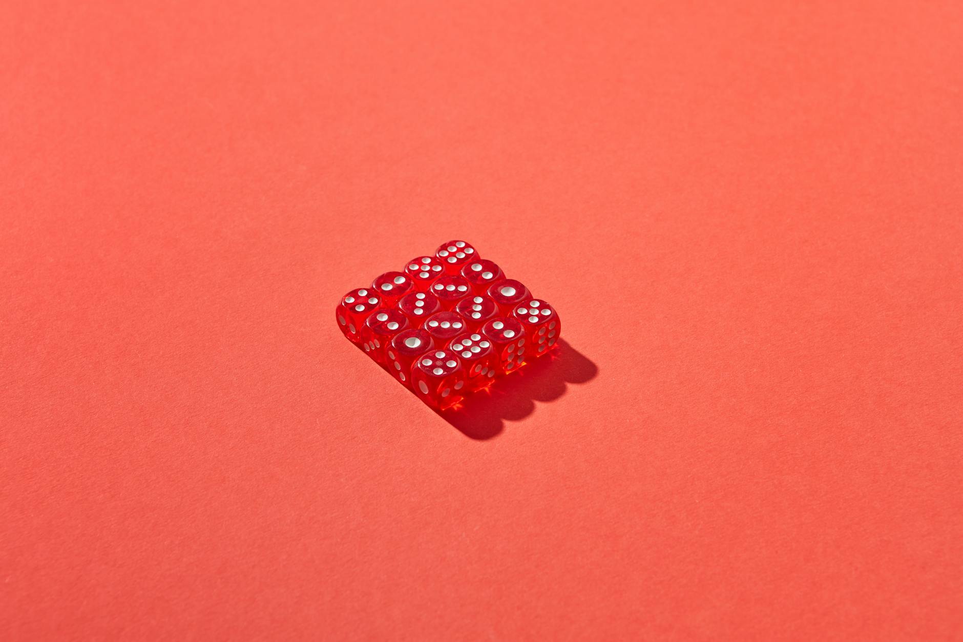 A set of red dice in shadow on a bold red background, creating a striking geometric design.