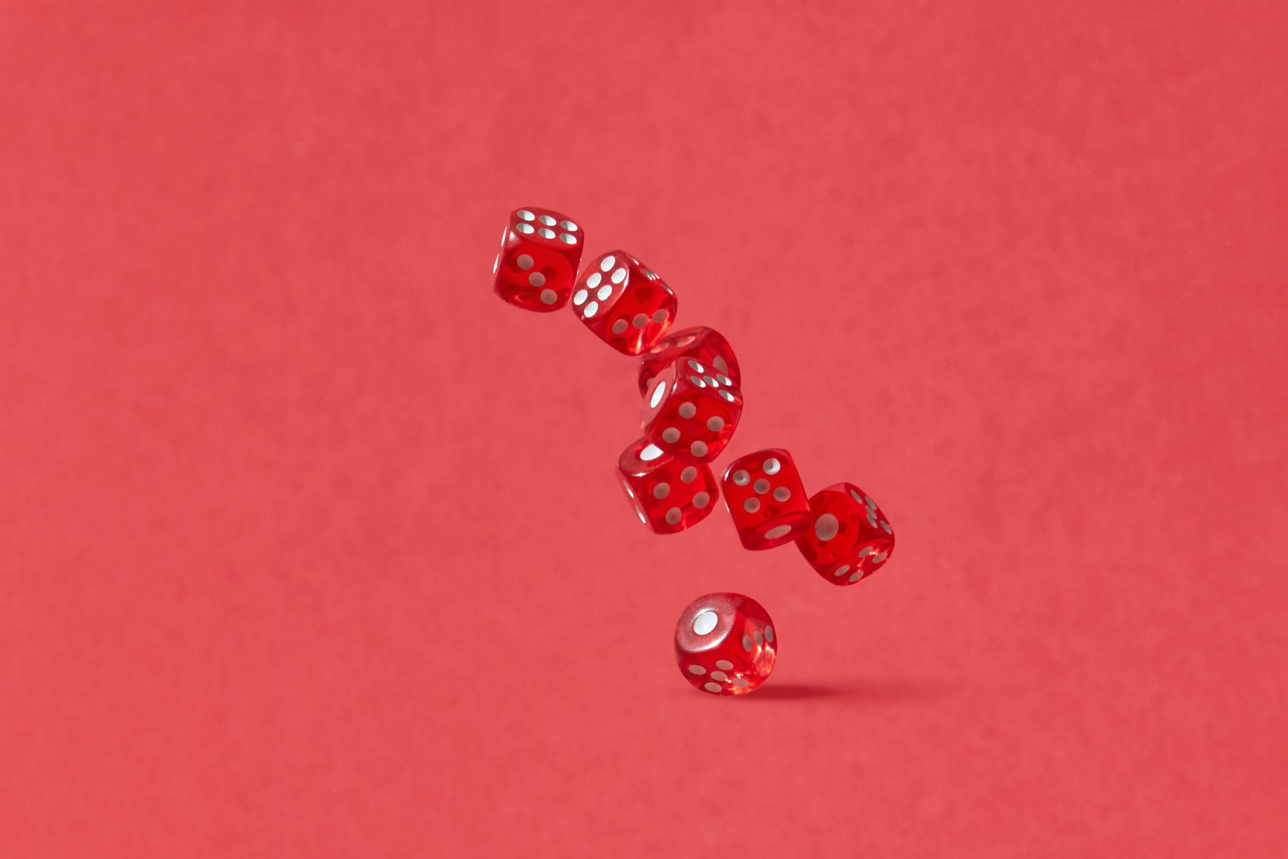 Dynamic shot of red dice tumbling mid-air against a crimson backdrop, perfect for gaming themes.