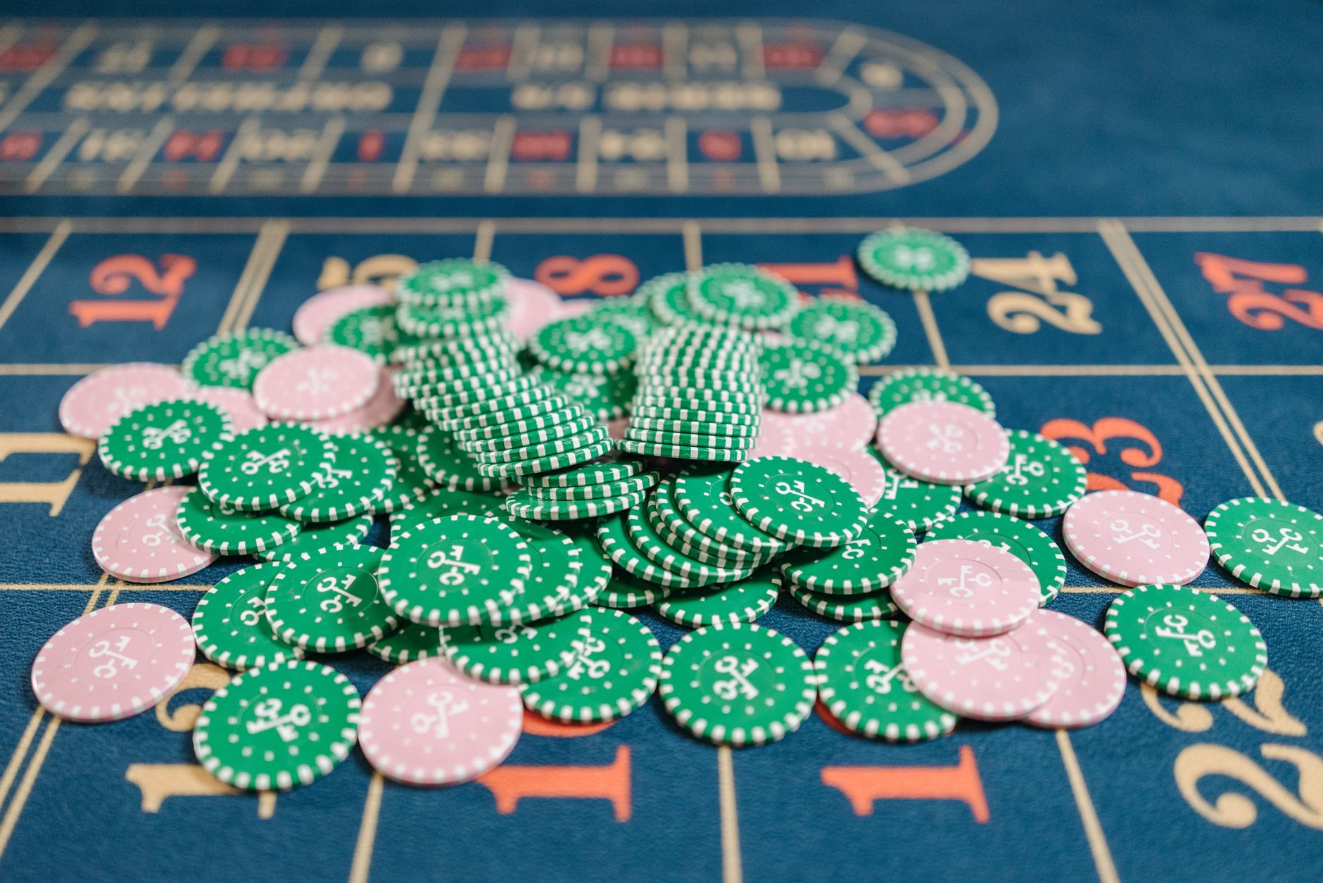 Close-up of a roulette table with a pile of green and pink poker chips.