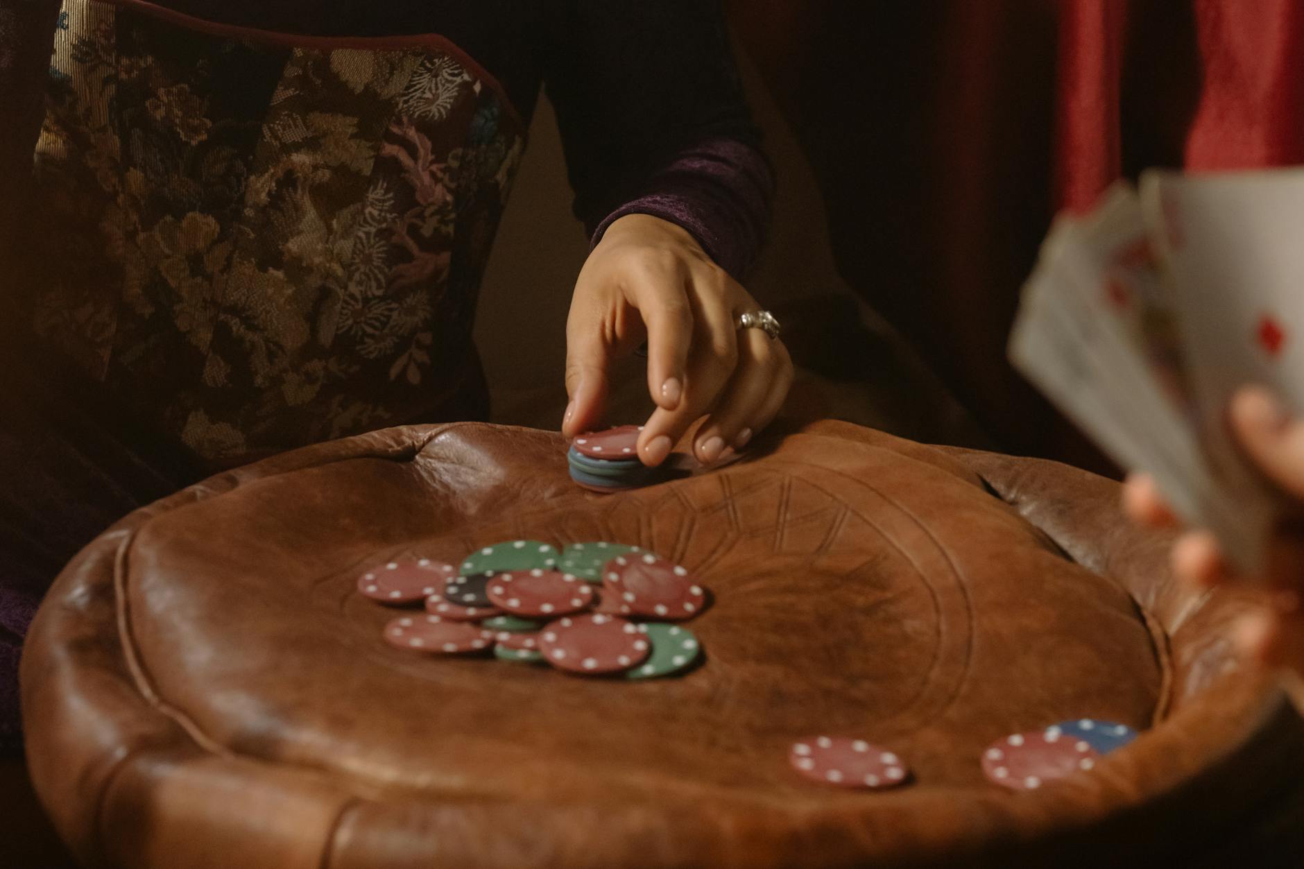 A close-up shot of poker chips on a table with hands holding cards, capturing a moment of gameplay.