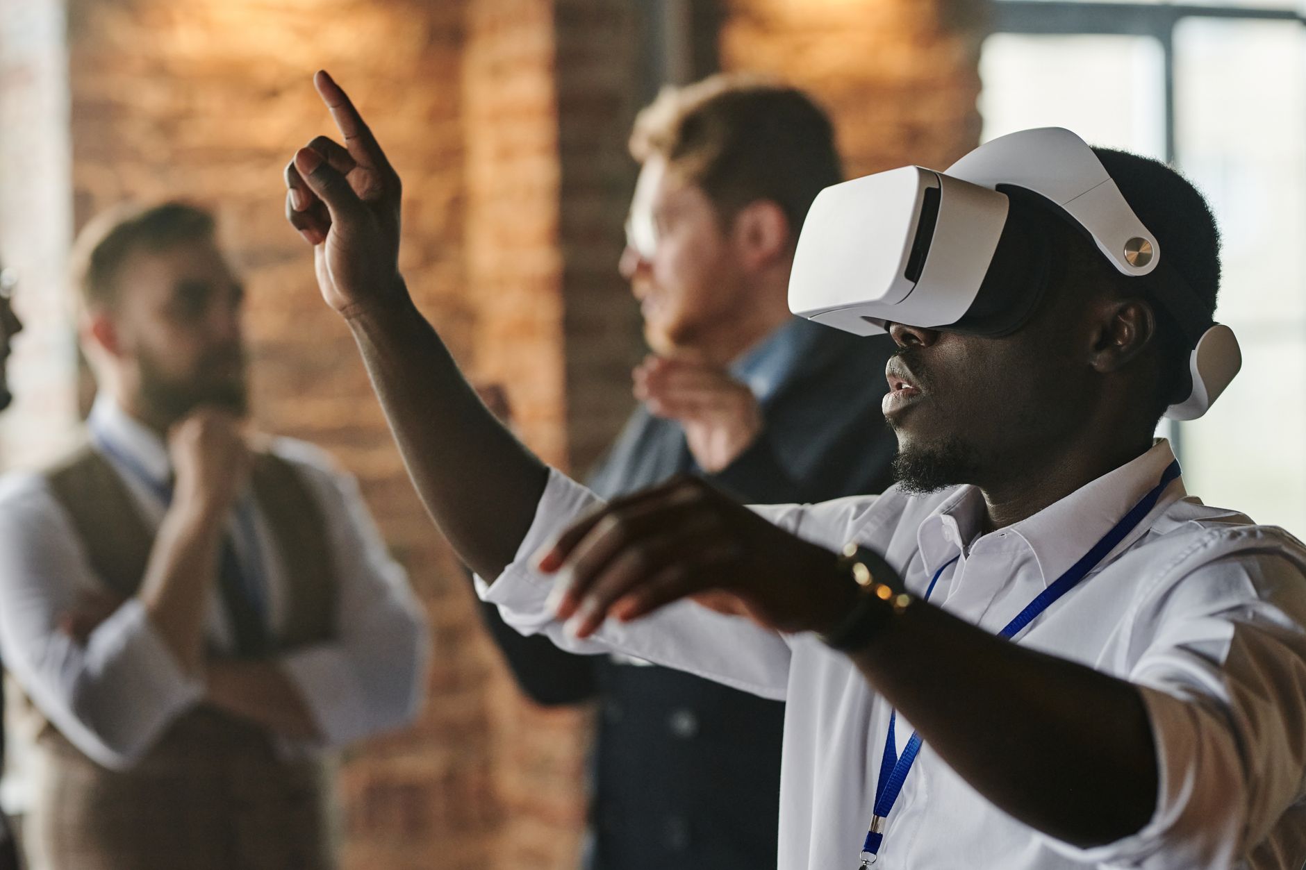 African American man using VR headset in a business meeting with colleagues in the background.