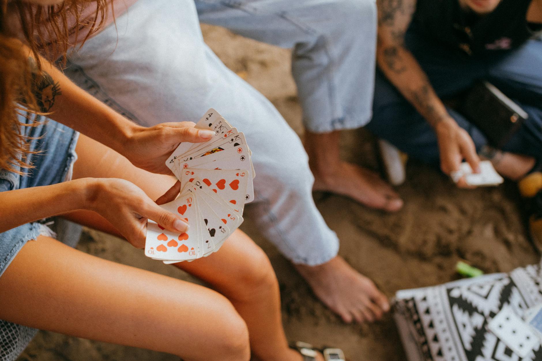 A group of friends enjoying a card game on the sand, showcasing leisure and camaraderie.