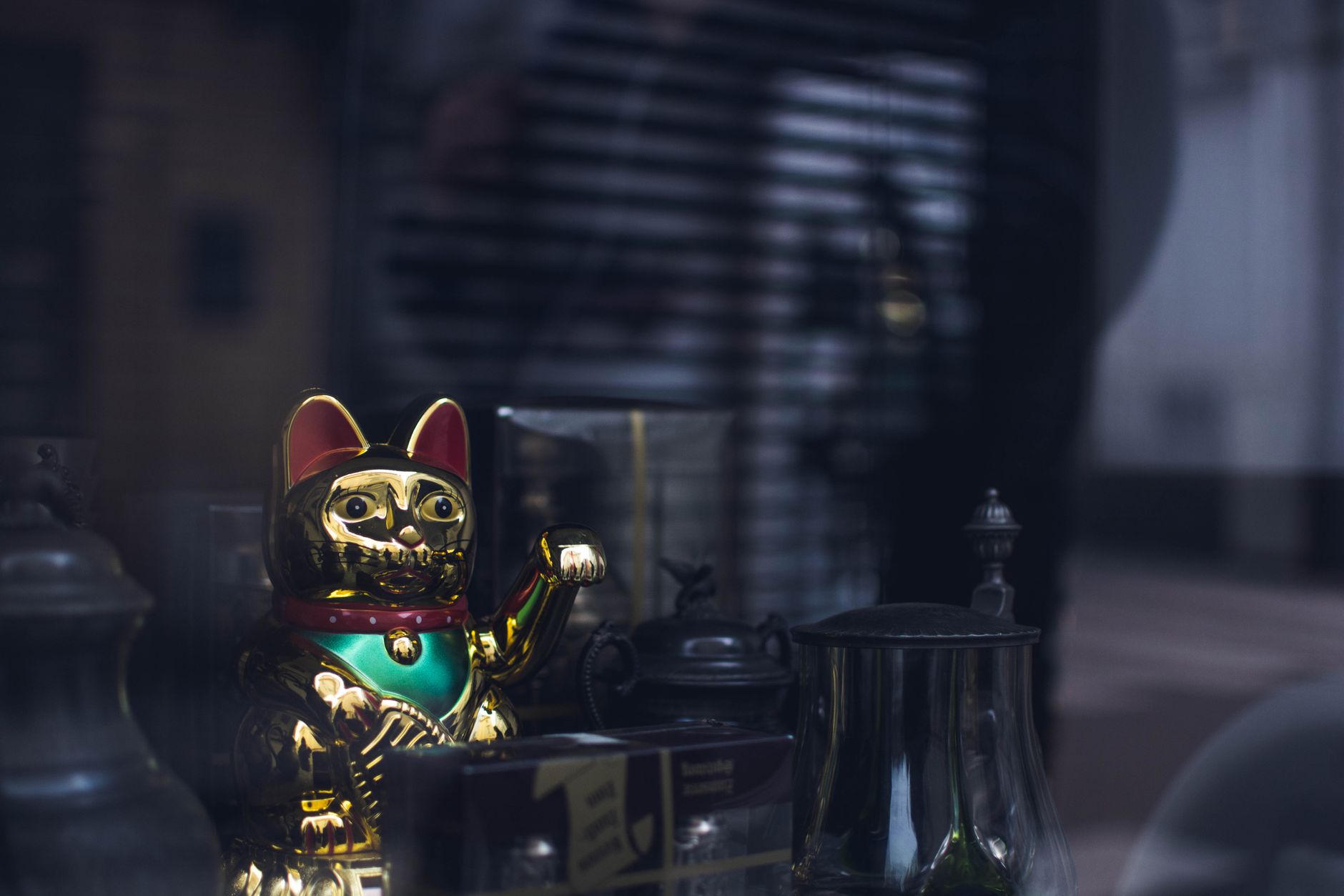 Golden maneki neko surrounded by antiques in a shop window.